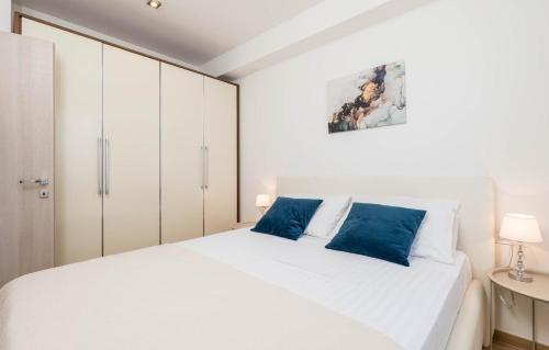 a bedroom with a white bed with blue pillows at Cres Sea & Sunset View in Cres