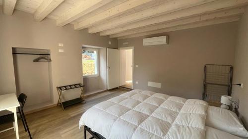 a bedroom with a white bed and a desk and a window at Da Teo & Lisa in Vignone