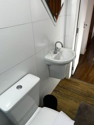 a white bathroom with a toilet and a sink at RCM Vilas - Casa Descolada in Joinville
