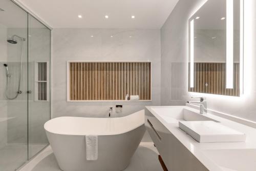 a white bathroom with a tub and a sink at Monthez Hotel & Eventos in Brusque