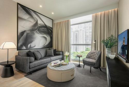 a living room with a couch and a chair at Ascott Orchard Singapore in Singapore