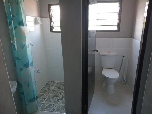 a bathroom with a toilet and a shower at TN Apartments deviat in Diani Beach