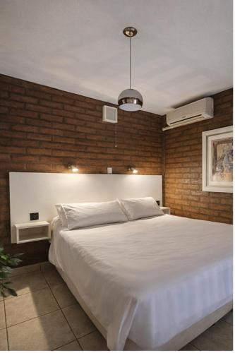 a bedroom with a large white bed and a brick wall at El Paso departamentos in San Juan