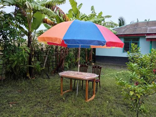 a table with a colorful umbrella in the grass at Bonolota Eco Villa in Mongla