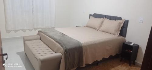 a bedroom with a bed with a bench and a window at Recanto do Araguaia in Aragarças