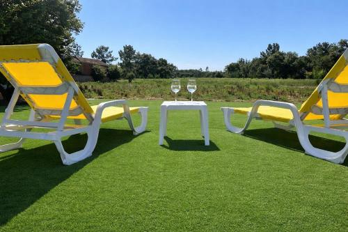 two chairs and a table with wine glasses on the grass at Casa da Tia in Poutena