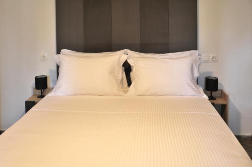 a bed with white sheets and pillows in a room at X N Skiathos in Skiathos