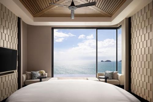 a bedroom with a large bed and a large window at Conrad Koh Samui in Taling Ngam Beach