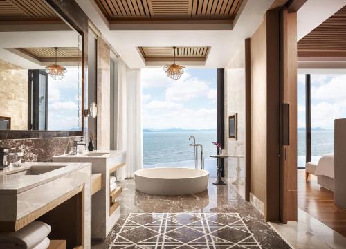 a bathroom with a tub and a view of the ocean at Conrad Koh Samui in Taling Ngam Beach