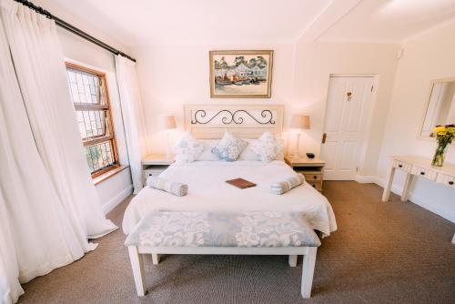 a white bedroom with a large bed and a window at La Vista Lodge in Plettenberg Bay
