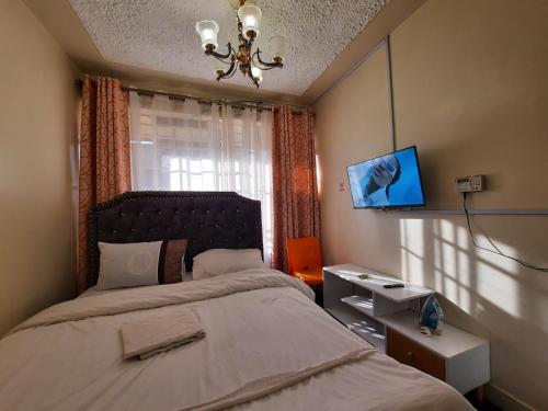 a bedroom with a bed with a chandelier and a window at Goodlife Studio - NRS Kinoo in Rungiri