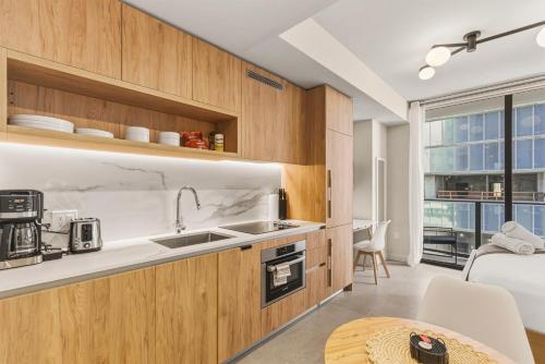 a kitchen with wooden cabinets and a sink and a table at Luxury Studio Steps from Bayfrontpark in Miami