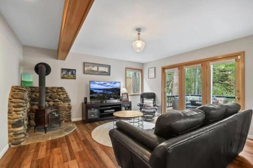 a living room with a leather couch and a fireplace at River Rock House-Deck-BBQ-Forest Trails & Views! in South Lake Tahoe