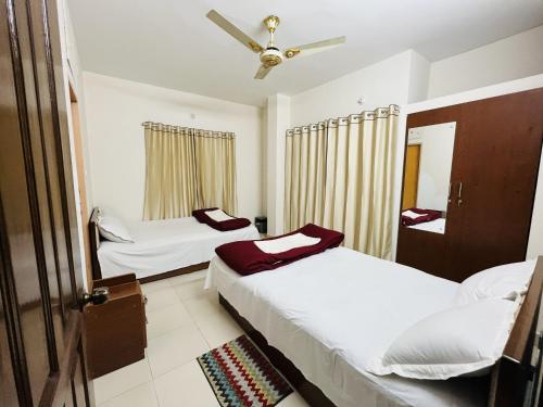 a bedroom with two beds and a ceiling fan at Tourist Home in Ābdullāpur