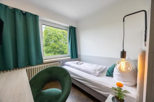 a small room with a bed and a green chair at Hotel Am Martinsberg in Andernach
