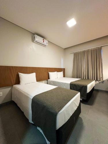 a hotel room with two beds and a window at Hotel Essência Campo Erê in Campo Erê