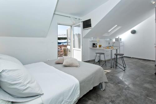 a white bedroom with a bed and a table at Core of Hvar Old Town in Hvar