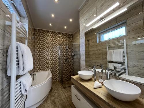 a bathroom with a tub and a sink and a tub and a mirror at Milano Vendégház in Bakonybél