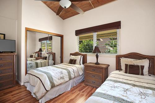 a bedroom with two beds and a dresser and a mirror at Makahuena at Poipu in Koloa