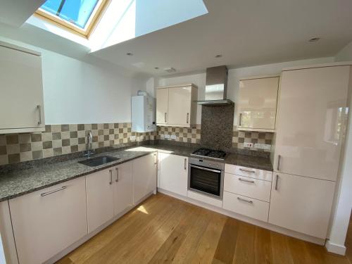 a large kitchen with white cabinets and a skylight at Lovely Central Romsey Apartment in Romsey