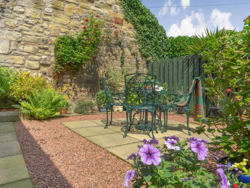 a table and chairs in a garden with flowers at Harry's Den in Alnwick