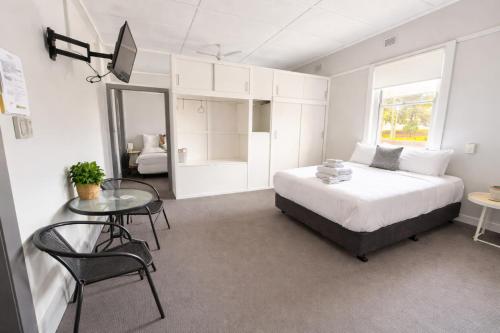 a bedroom with a bed and a table and a window at Federal Hotel Mudgee in Mudgee