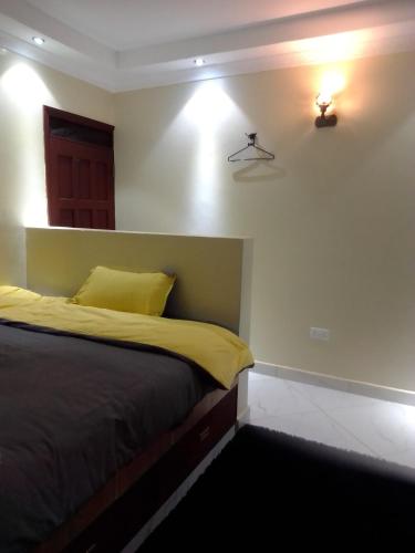 a bedroom with a bed with yellow sheets and lights at Wasini gardens,, vingazini in Mtwapa