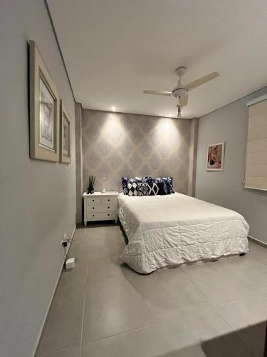 a bedroom with a white bed and a ceiling fan at Apto Moderno no Centro - Completo e Confortável in Americana