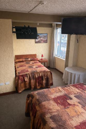 a hotel room with two beds and a flat screen tv at Hostal Santo Domingo in Cusco