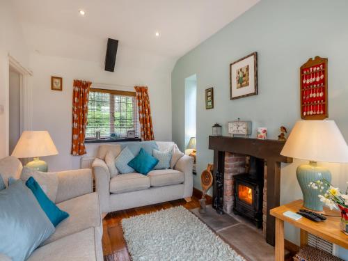 a living room with a couch and a fireplace at Little Crawfish Cottage in Thursford