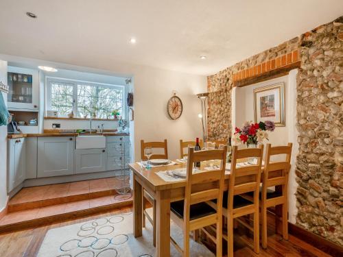 a kitchen and dining room with a wooden table and chairs at Little Crawfish Cottage in Thursford