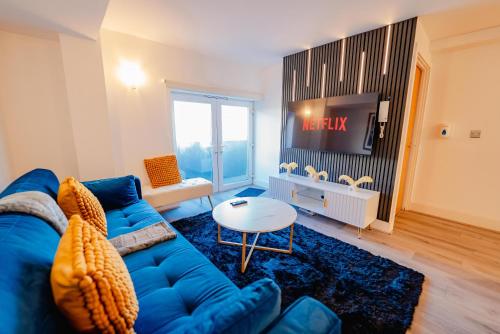 a living room with a blue couch and a tv at Modern 2 BR 2 Bath Flat With Balcony & Fast WiFi in Cardiff