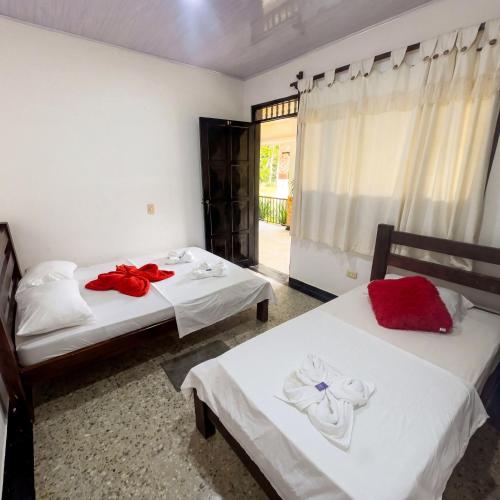 a bedroom with two beds with red pillows on them at Lagos de Samarcanda in Cumaral