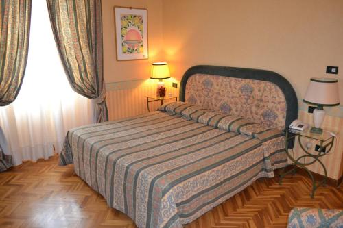 a bedroom with a bed and two lamps and a window at Hotel Giglio in Montecatini Terme