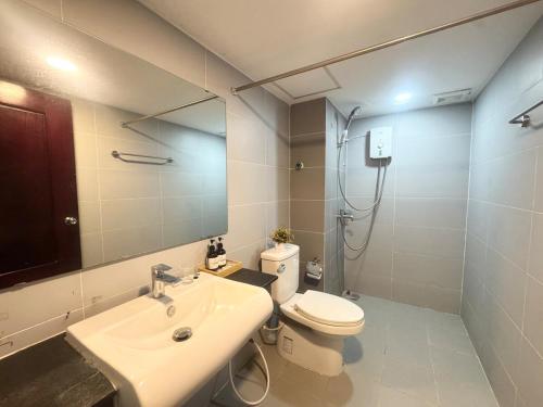 a bathroom with a sink and a toilet and a mirror at Spacious 5BR Townhouse in Central Phnom Penh in Phnom Penh