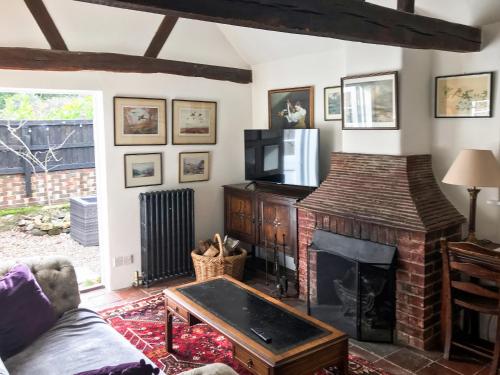 a living room with a fireplace and a tv at Old Rectory Cottage in Fernhurst
