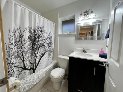 a bathroom with a shower curtain with a toilet and a sink at Cozy Cabin Near Walking Trails And Beaches! in Ucluelet