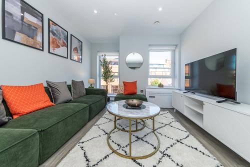 a living room with a green couch and a table at Brand New Flat with AC 5-Min Walk to Town Centre - Pass the Keys in Reading
