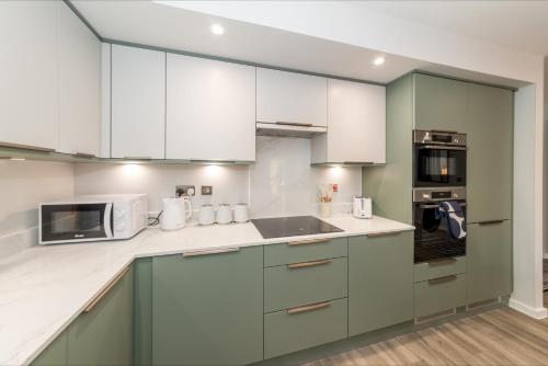 a kitchen with green and white cabinets and a microwave at Brand New Flat with AC 5-Min Walk to Town Centre - Pass the Keys in Reading