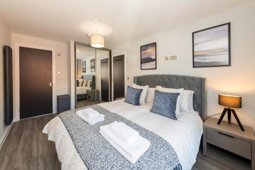 a bedroom with a large bed with blue pillows at Brand New Flat with AC 5-Min Walk to Town Centre - Pass the Keys in Reading