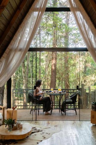 a woman sitting at a table on a screened in porch at Lohma Nature in Gramado