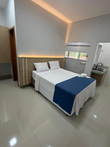 a bedroom with a large bed with a blue blanket at Hotel Marinho in Gurupi