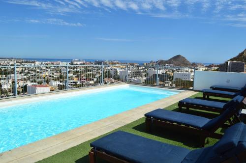 a swimming pool with two chairs and a view of a city at The Residences Apart-Hotel By Morgan in Cabo San Lucas