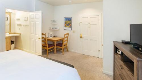 a bedroom with a bed and a table and a television at Cimarron Lodge 50 by AvantStay Ski-InSki-Out Property in Complex w Two Hot Tubs in Telluride