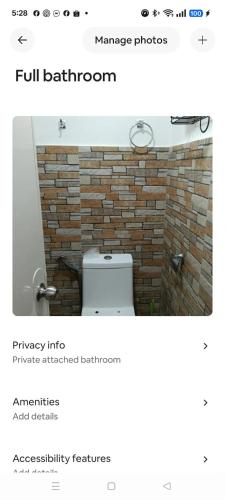 a bathroom with a toilet and a brick wall at Xavier Heights Gate 1 Pad in Cagayan de Oro