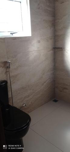 a bathroom with a black toilet and a window at Recanto do Araguaia in Aragarças