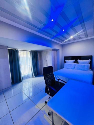 a blue room with a bed and a desk and a table at Modern Comfort, Easy Access Everywhere in Vanderbijlpark