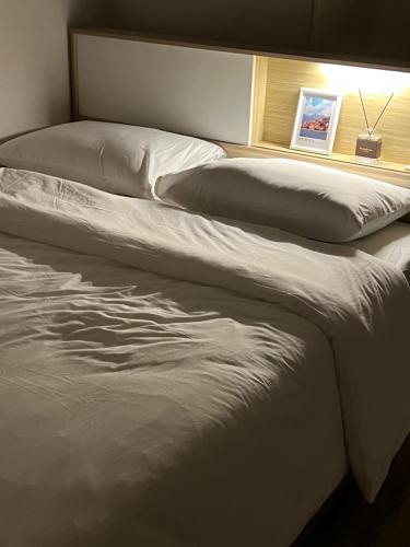 a bed with white sheets and pillows in a room at Stay Mokpo,2R1B,목포역,케이블카,동부시장,최대4인 in Mokpo