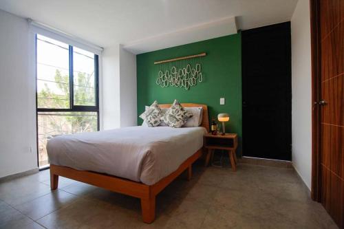 a bedroom with a large bed with a green wall at Tribu Santa Tere in Guadalajara