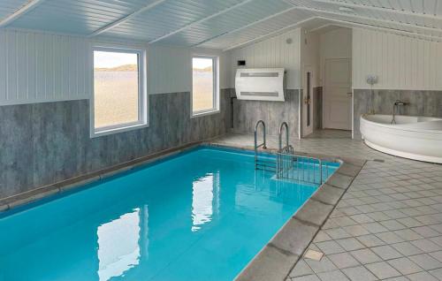 a bathroom with a tub and a large blue pool at Awesome Home In Hvide Sande With Sauna in Hvide Sande
